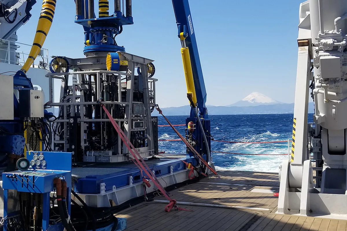 Subsea cobalt crust lander drill system, designed and built by Wassoc, sits on the back deck with ocean and volcano in background
